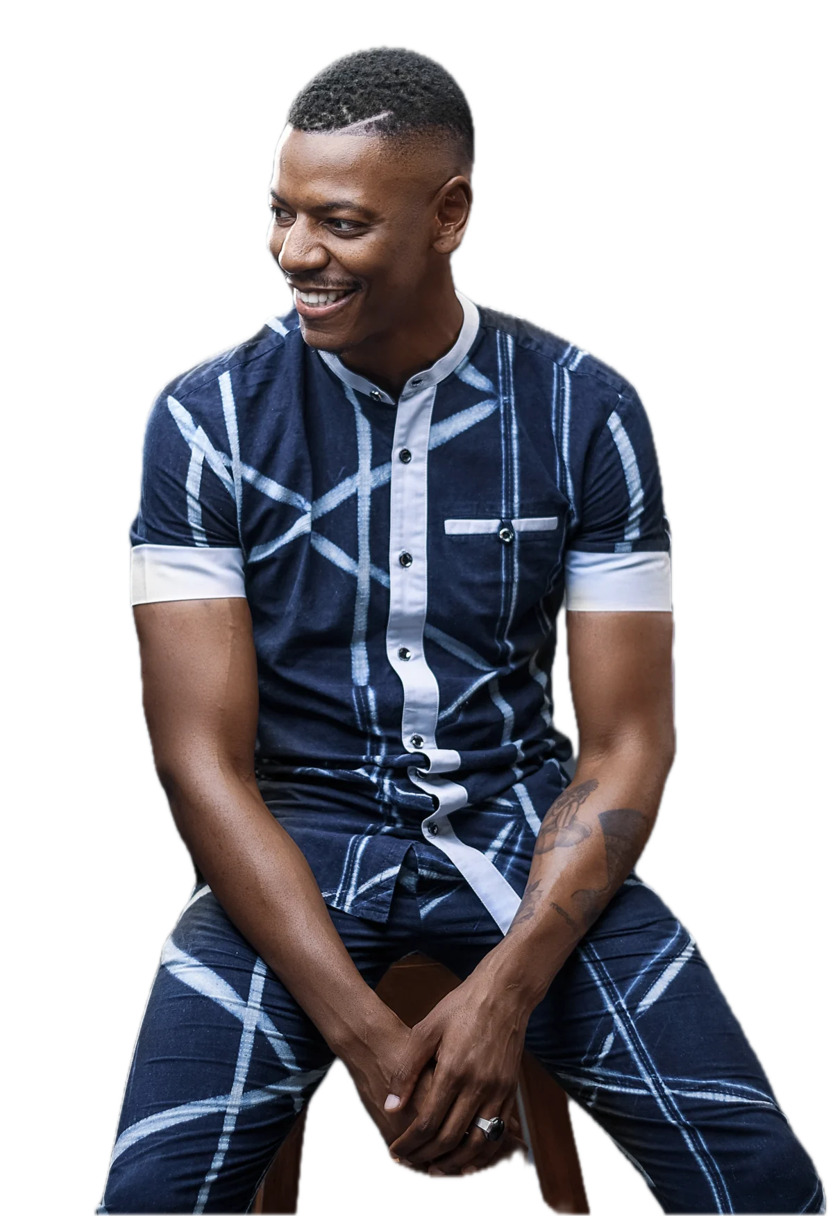 Yann Tassoua, assis, chemise indigo à lignes blanches, sourire, regard tourné vers la page